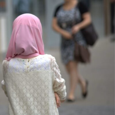 Ein Mädchen von hinten mit weißem Pulli und rosa Kopftuch (Hijab).