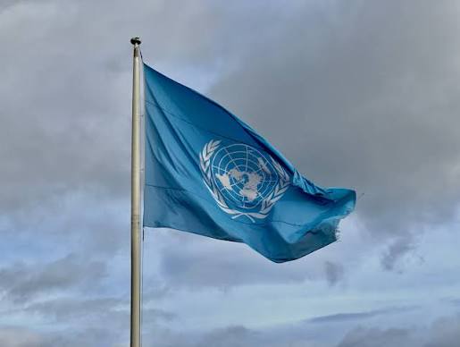 Die Flagge der Vereinten Nationen vor dunklen Wolken im Wind
